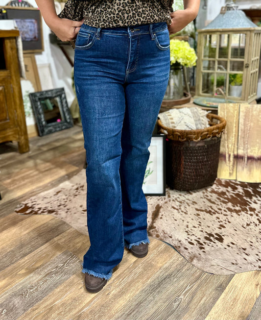 Person wearing blue jeans standing on a wooden floor with decorative elements in the background