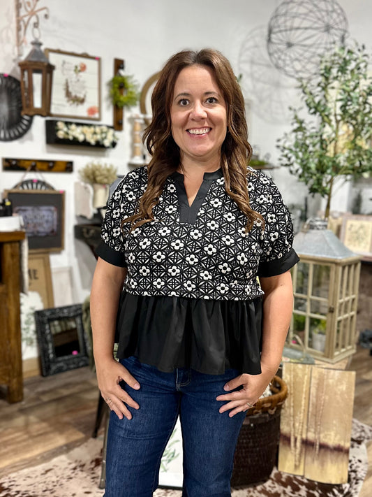 Woman wearing a black and white patterned blouse with blue jeans in a home decor store.