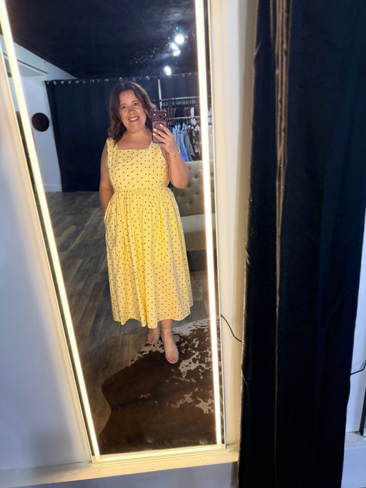 Woman taking a mirror selfie wearing a yellow dress with a pattern.